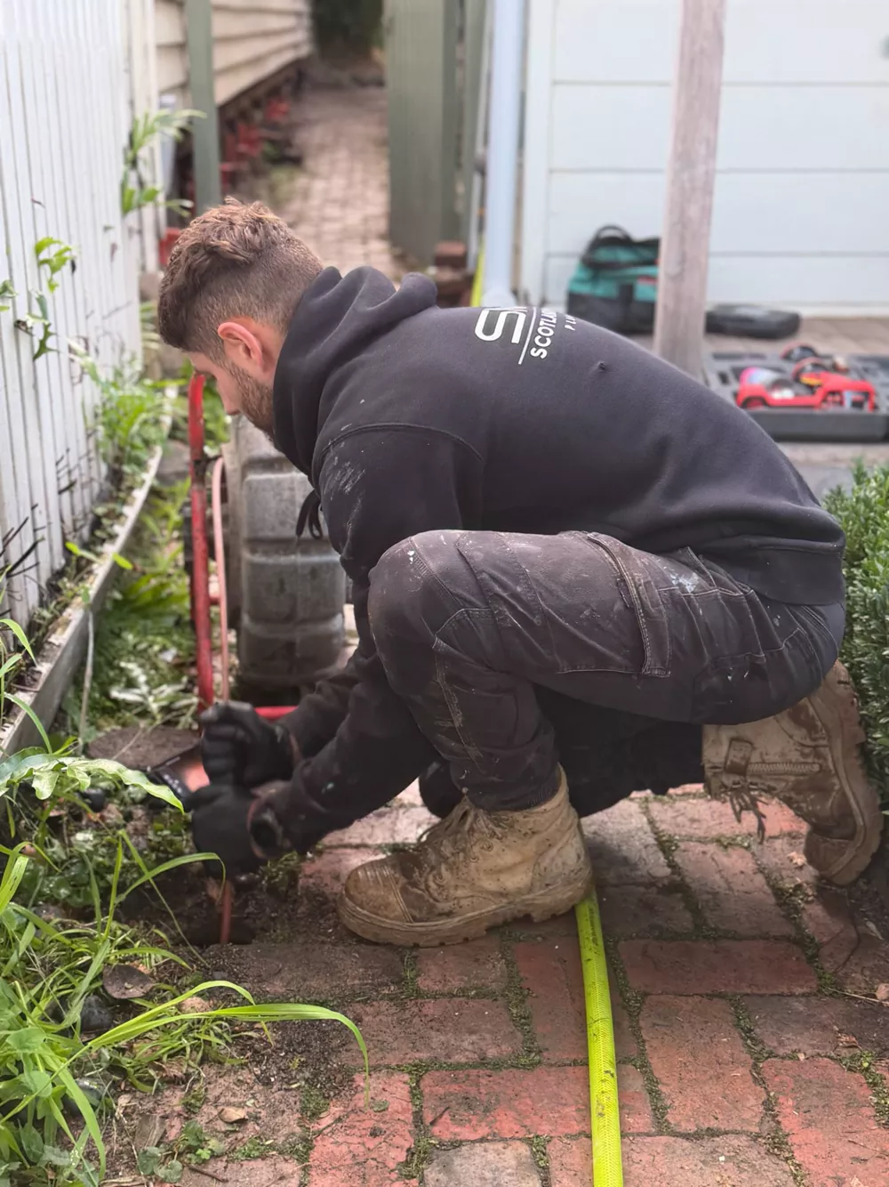 SMP plumber inspecting a stormwater drain down a side path